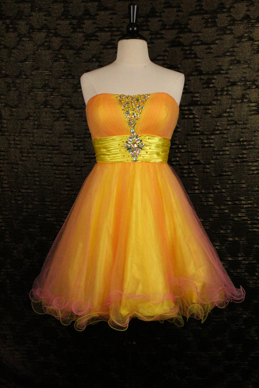 A strapless yellow and orange tulle homecoming dress displayed on a white mannequin torso against a dark textured background. The dress features a yellow satin waistband with a jeweled embellishment at the center bust.